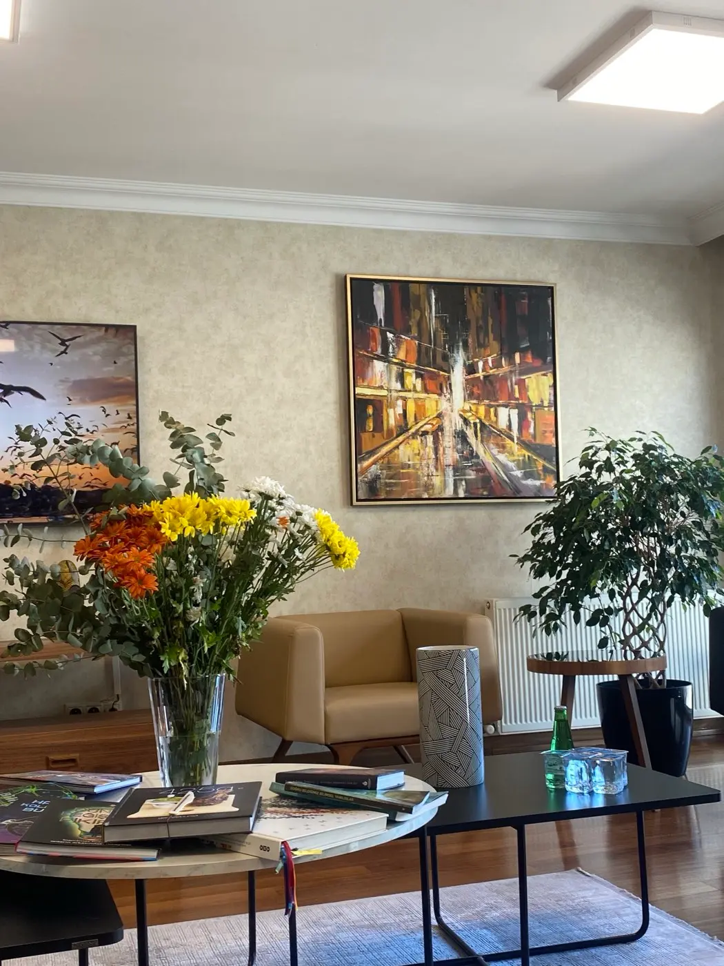 Kliniğin bekleme salonu — oturma grubu, tablolar ve çiçek düzenlemesi